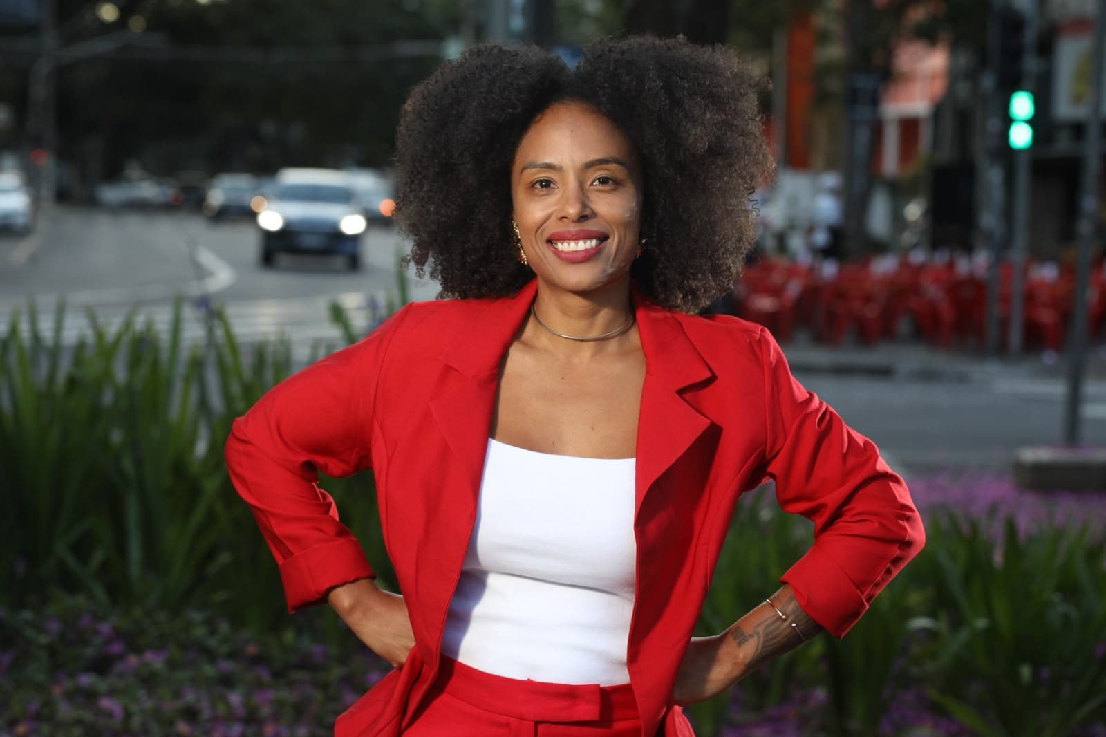 Retrato de estúdio de Jaque Medeiros, de braços cruzados, com blazer vermelho.